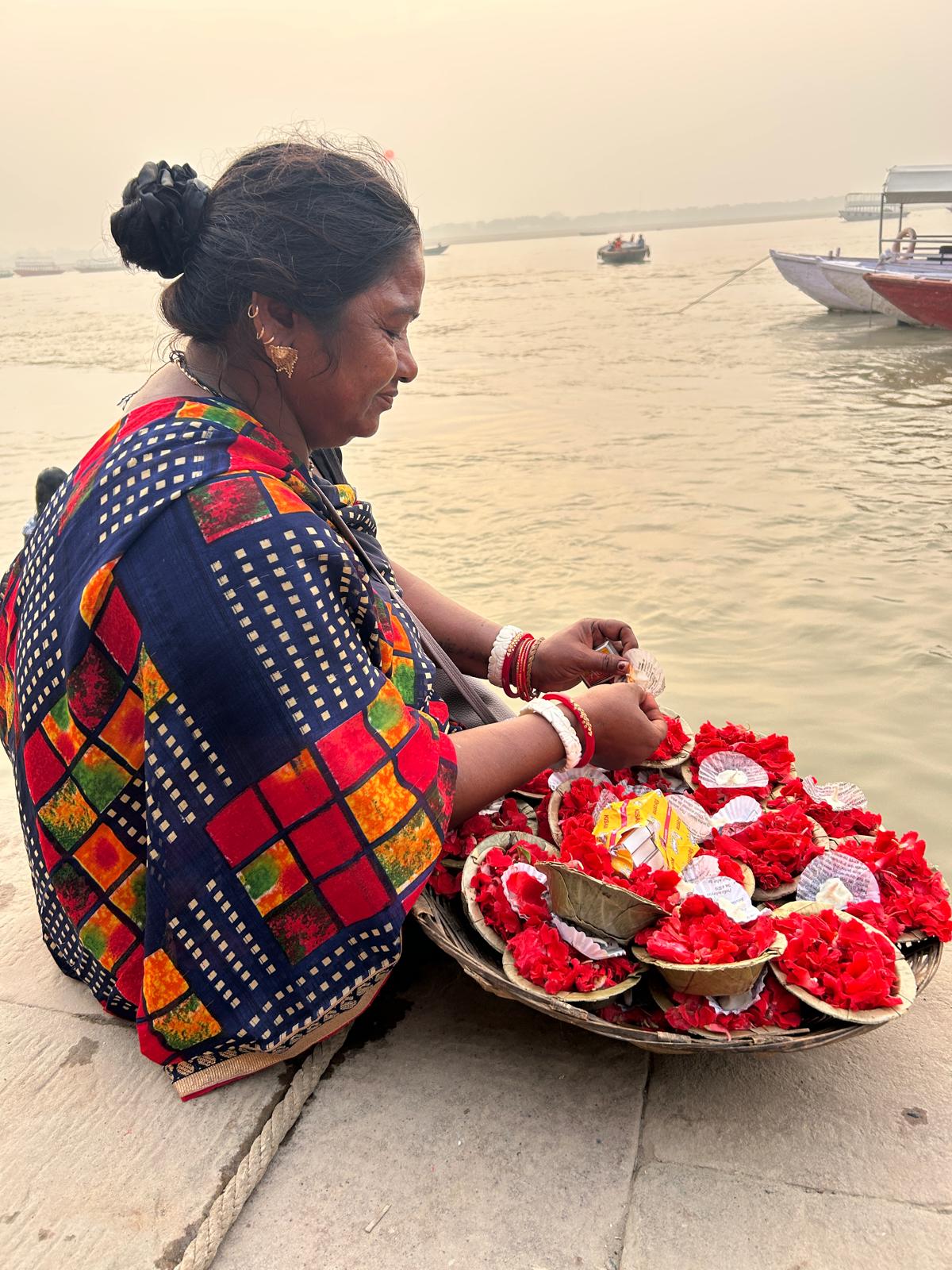 Mujer preparando ofrendas de flores junto al Ganges