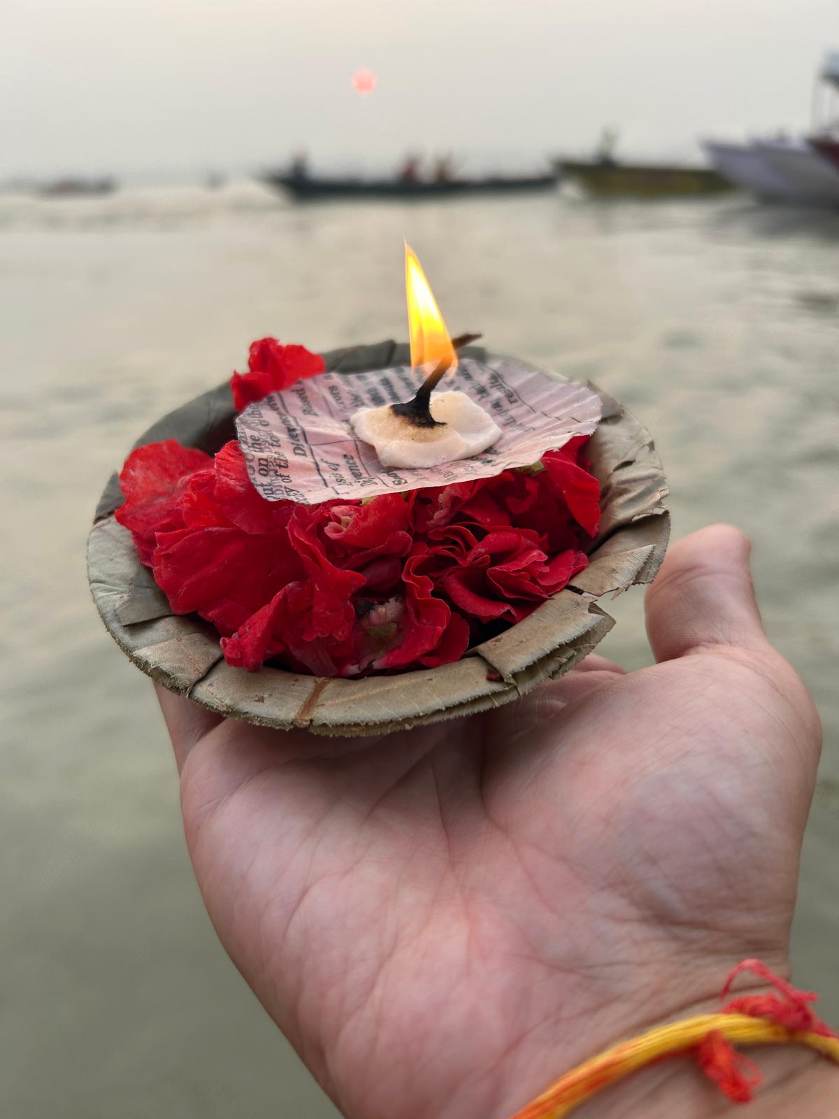 Ofrenda con diya y flores en el Ganges al amanecer
